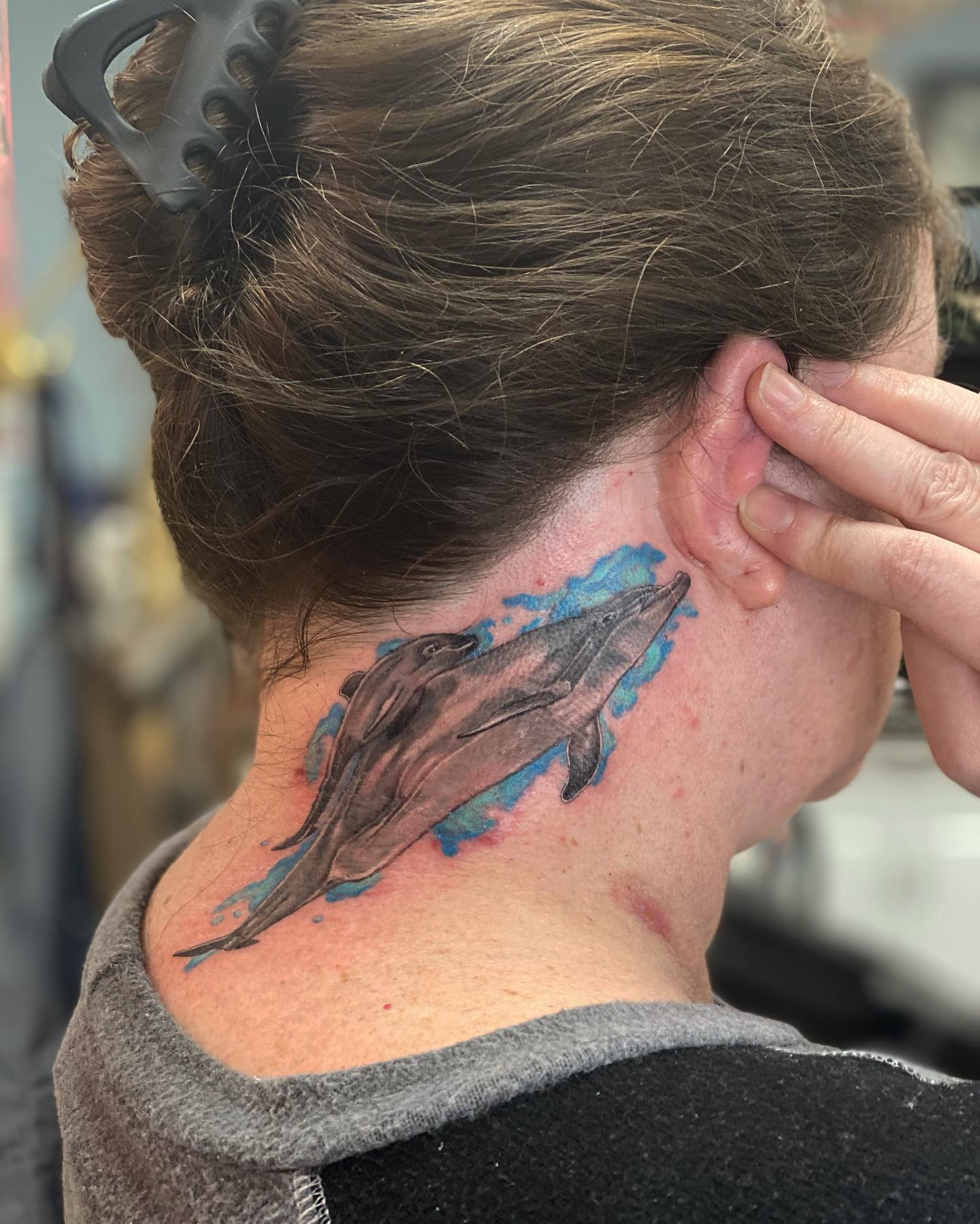 Diseño de tatuaje de ballena detrás de la oreja.