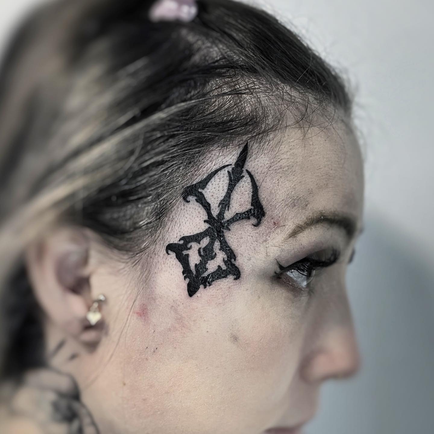 Símbolo de Berserk en una tatuaje en la cara