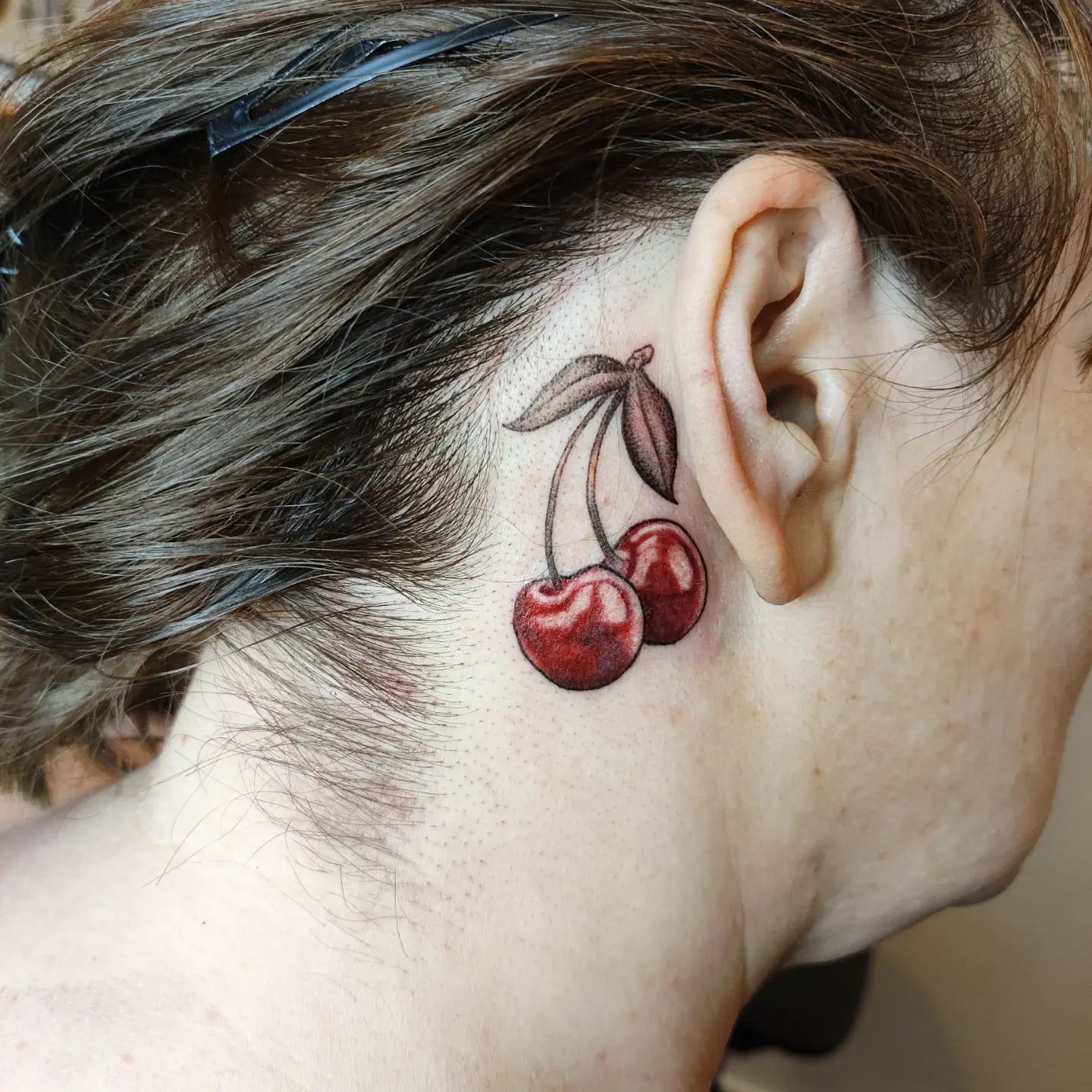 Tatuaje de cereza detrás de la oreja