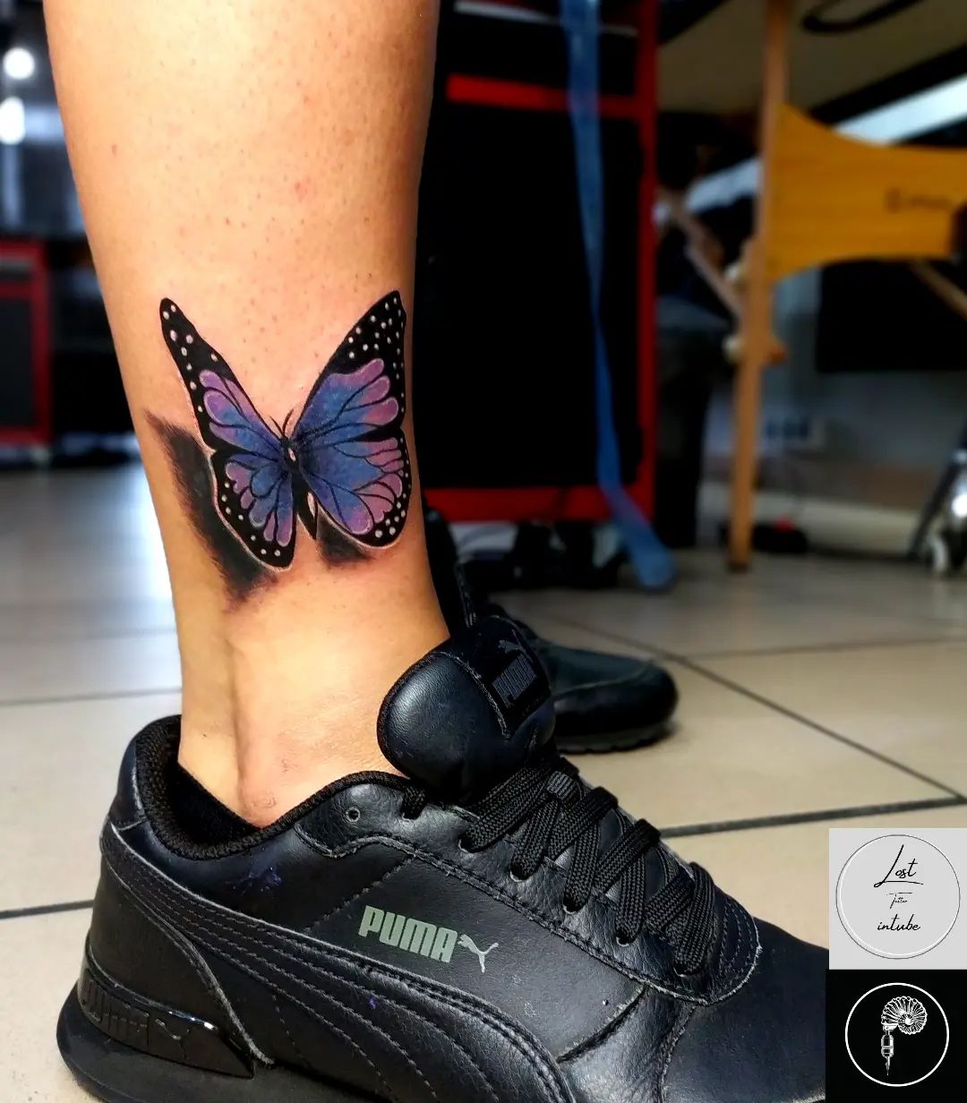 Tatuaje de mariposa morada en el tobillo.