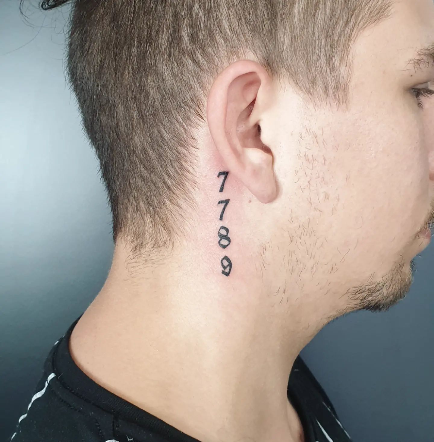 Tatuaje de números detrás de la oreja.