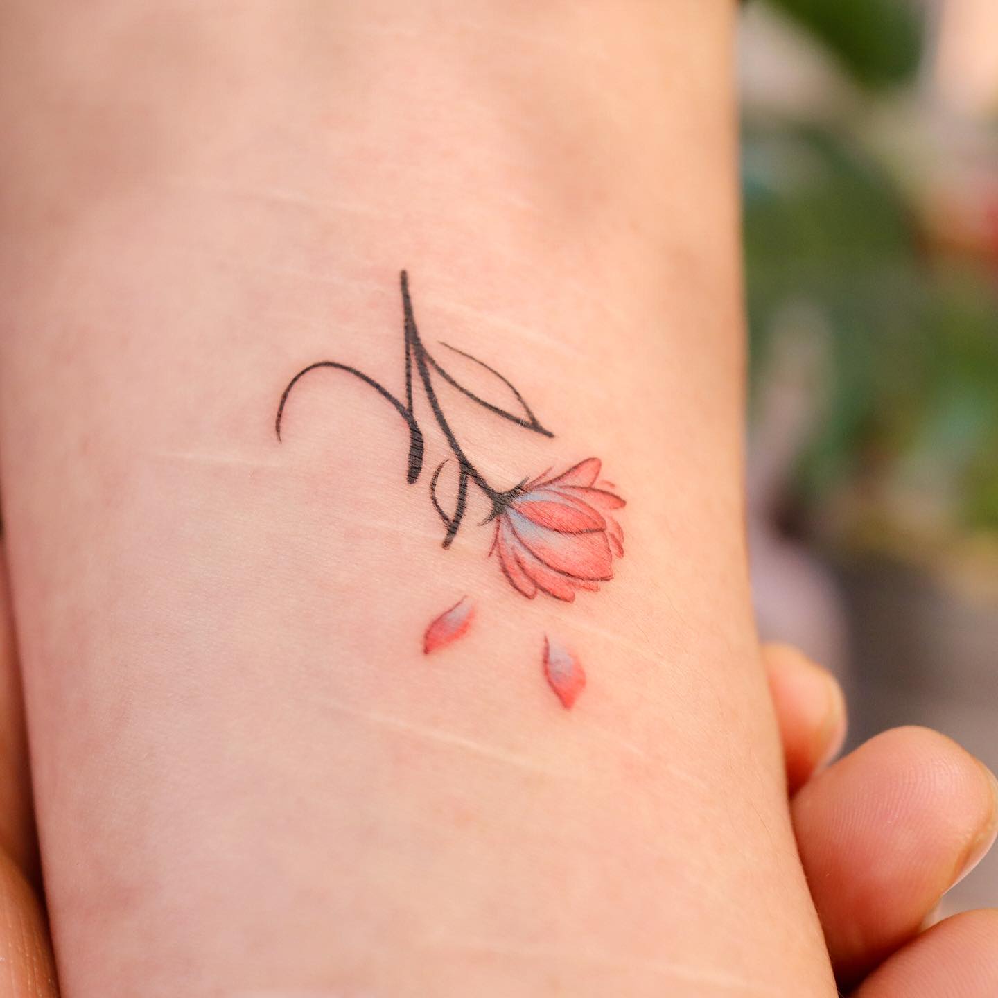 Tatuaje femenino de flores en la muñeca.