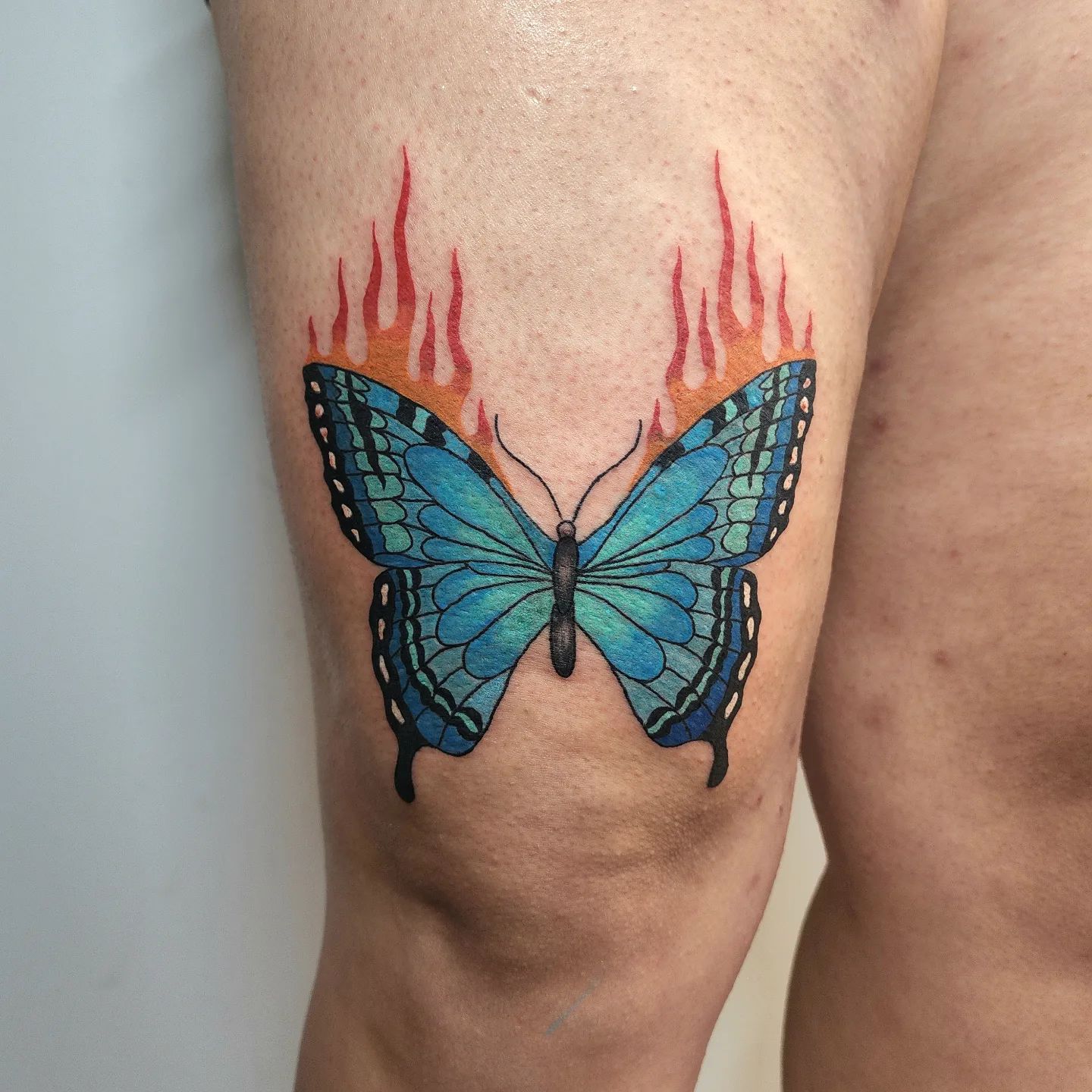 Mariposa azul tatuada sobre la rodilla