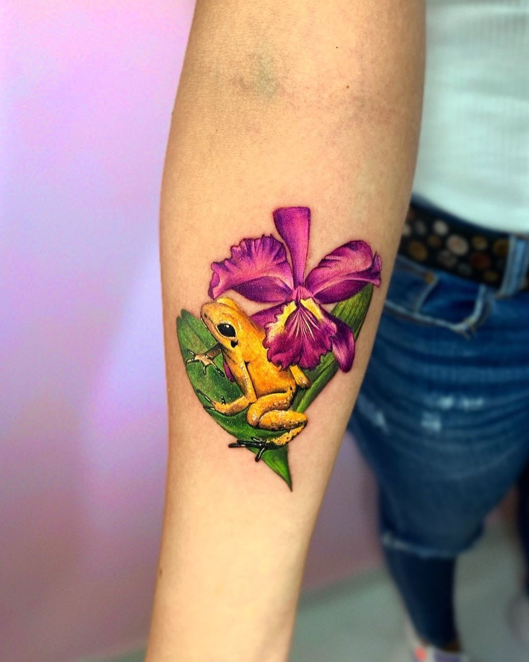 Tatuaje brillante de orquídea con una rana