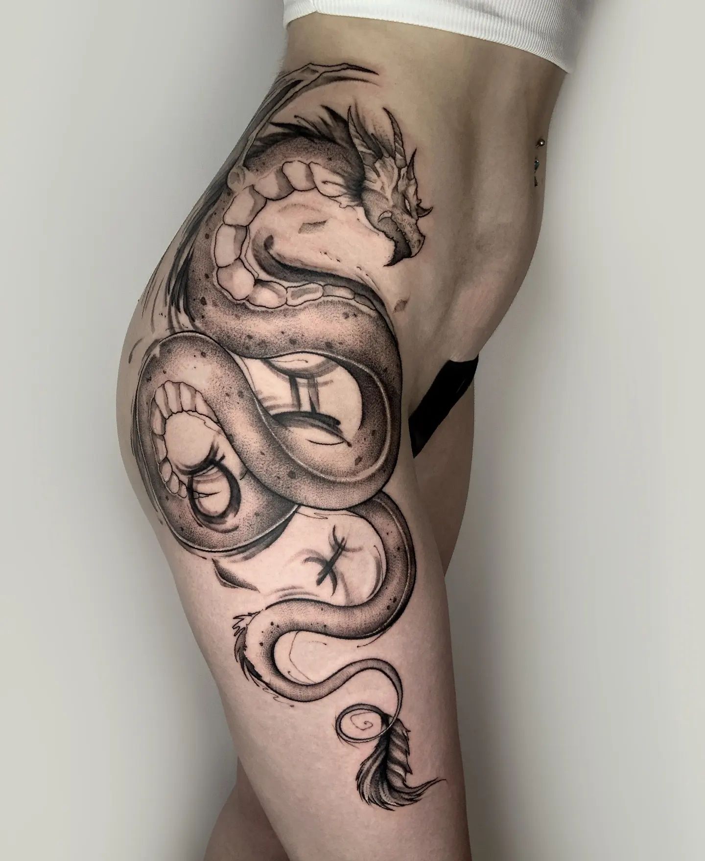 Tatuaje en la cadera de un dragón grande y negro.