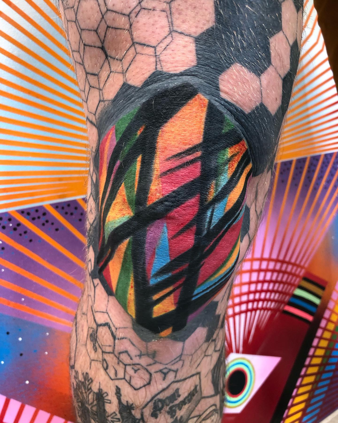 Tatuaje raro y colorido encima de la rodilla