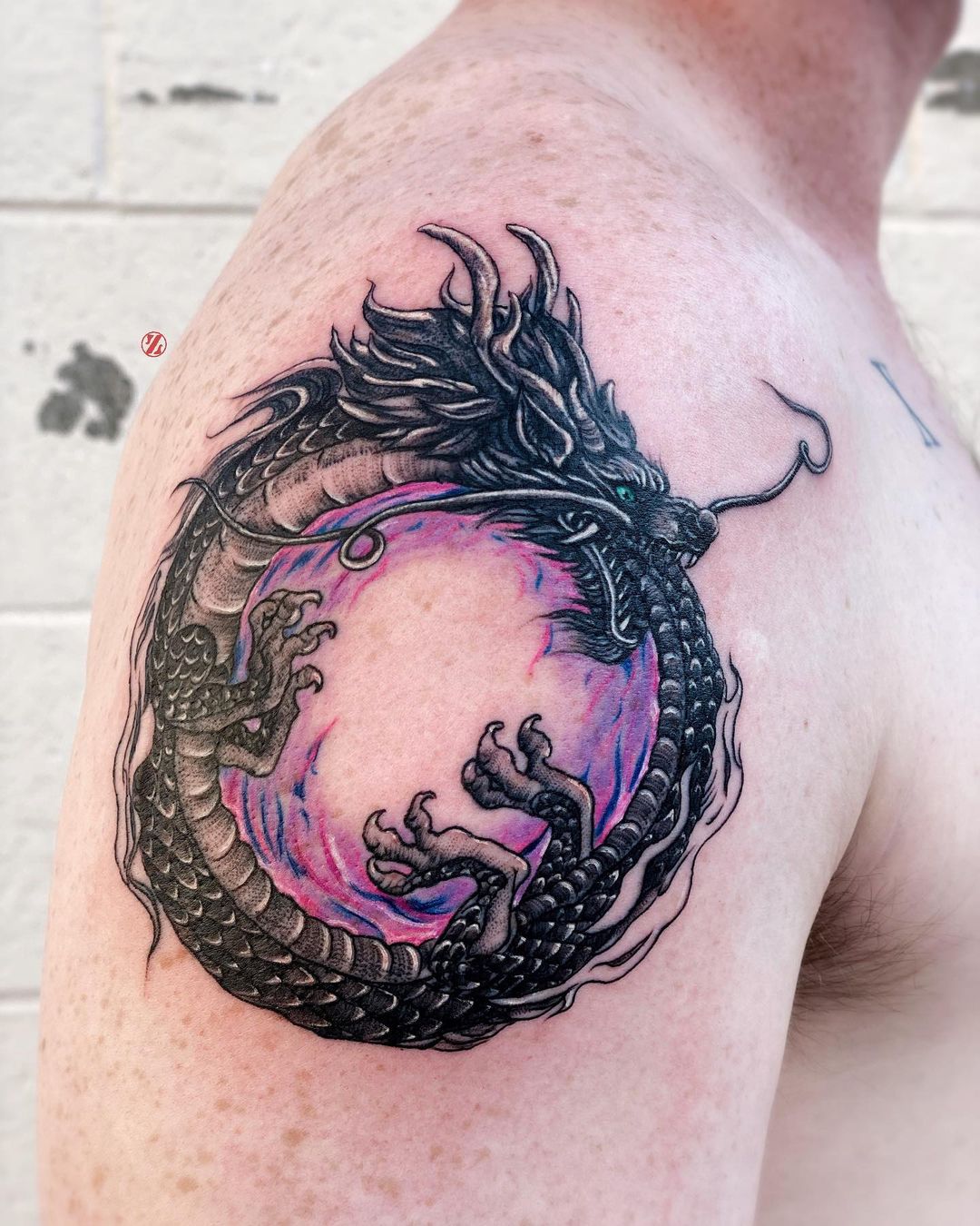 Gran tatuaje de Ouroboros colorido en el hombro.