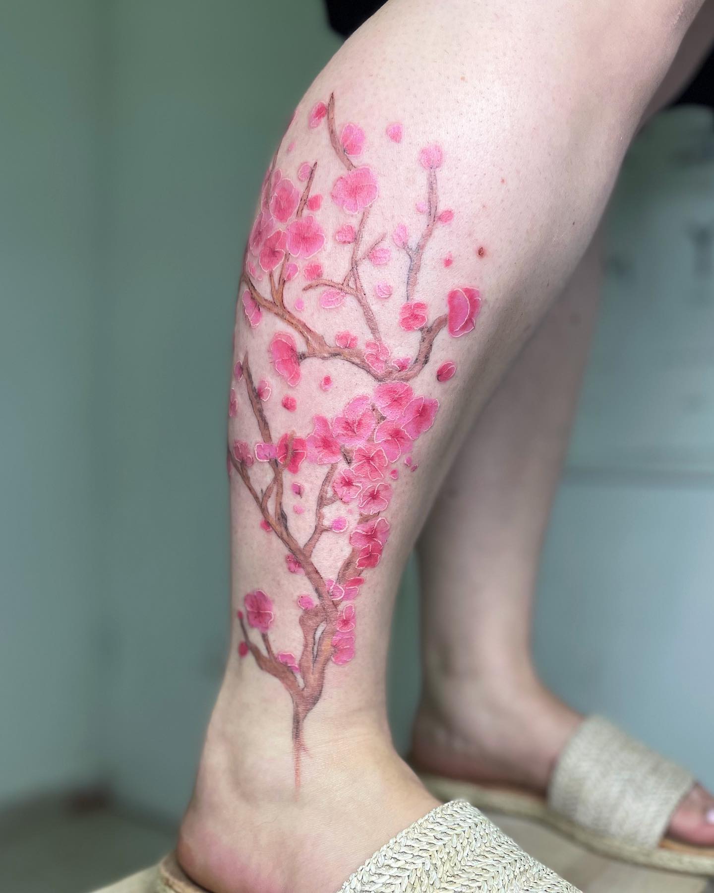 Tatuaje de flor de cerezo en la pierna.