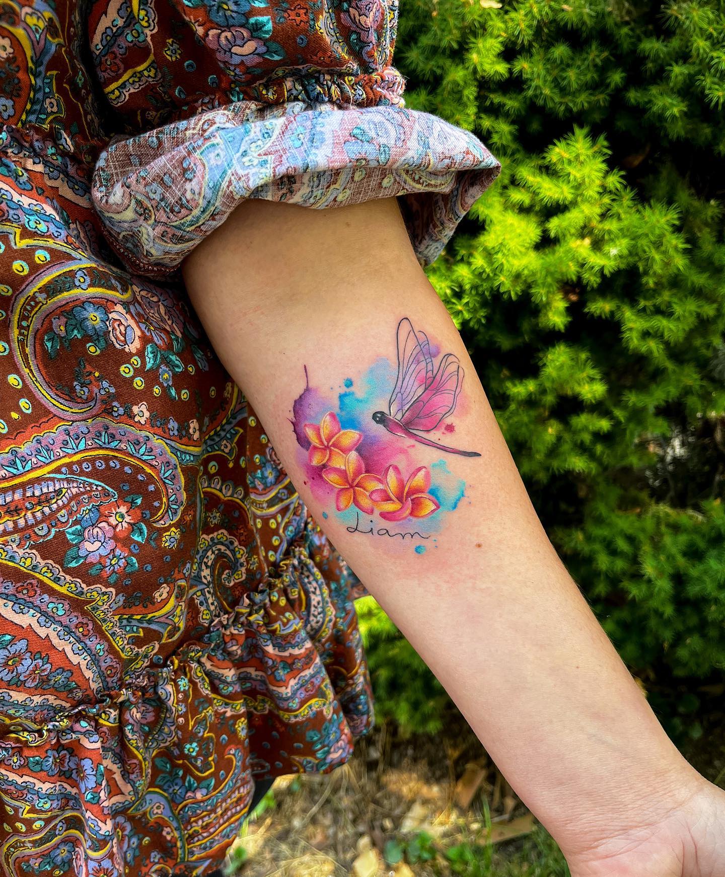 Tatuaje de libélula colorido en el brazo.
