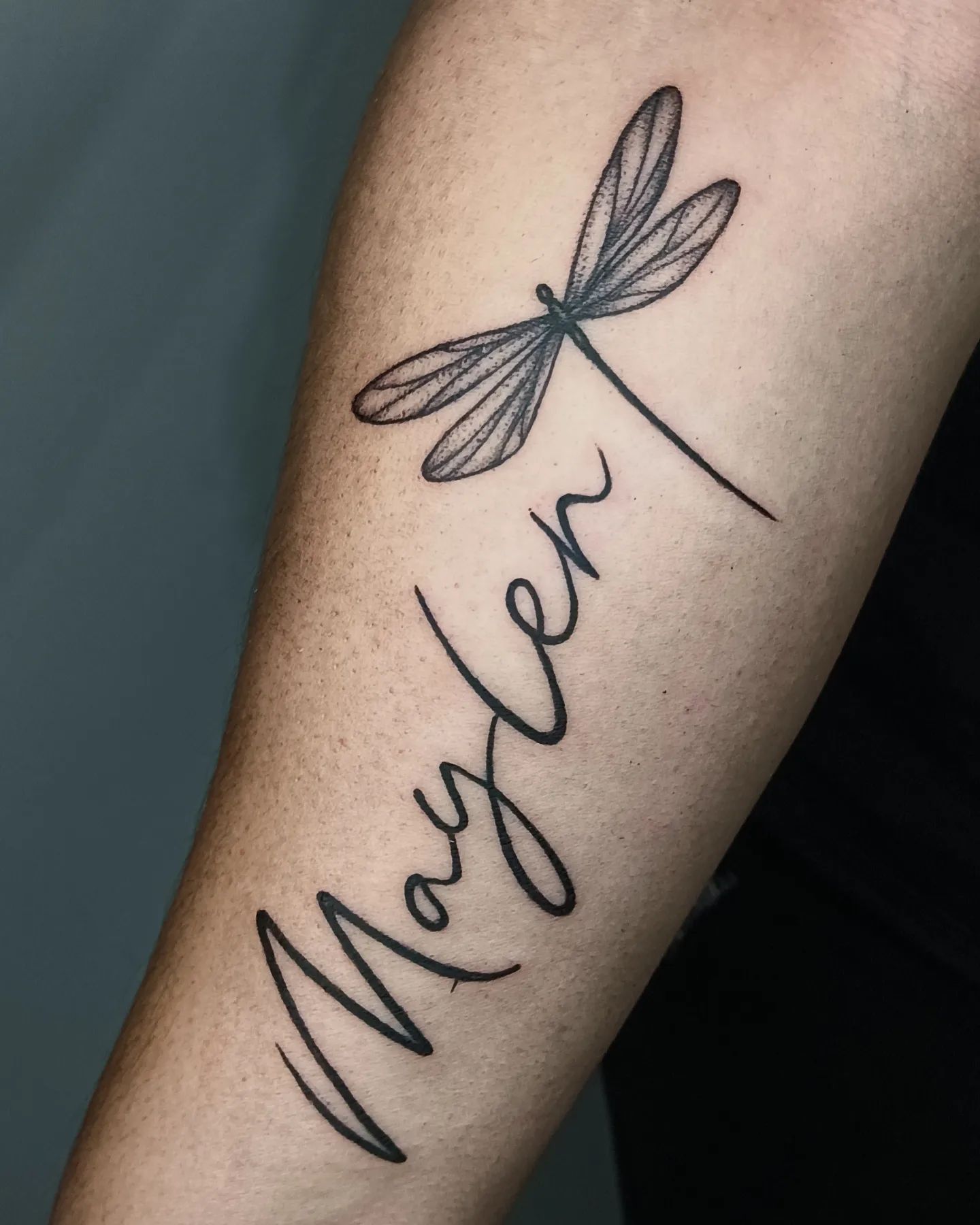 Tatuaje de libélula con impresión de nombre.
