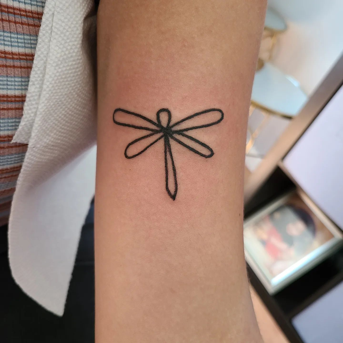 Tatuaje de pequeña libélula negra.