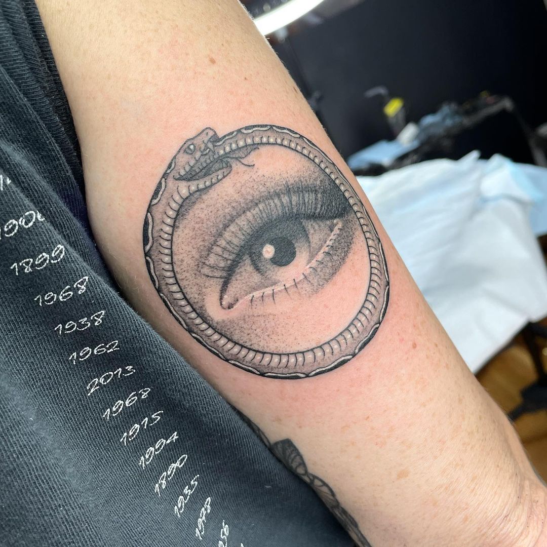Tatuaje detallado de Ouroboros con impresión de ojo.