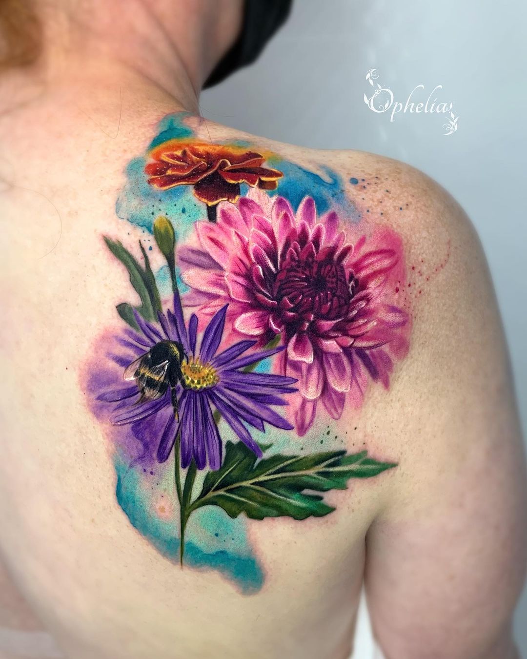 Tatuaje de flor de aster colorida en la espalda.