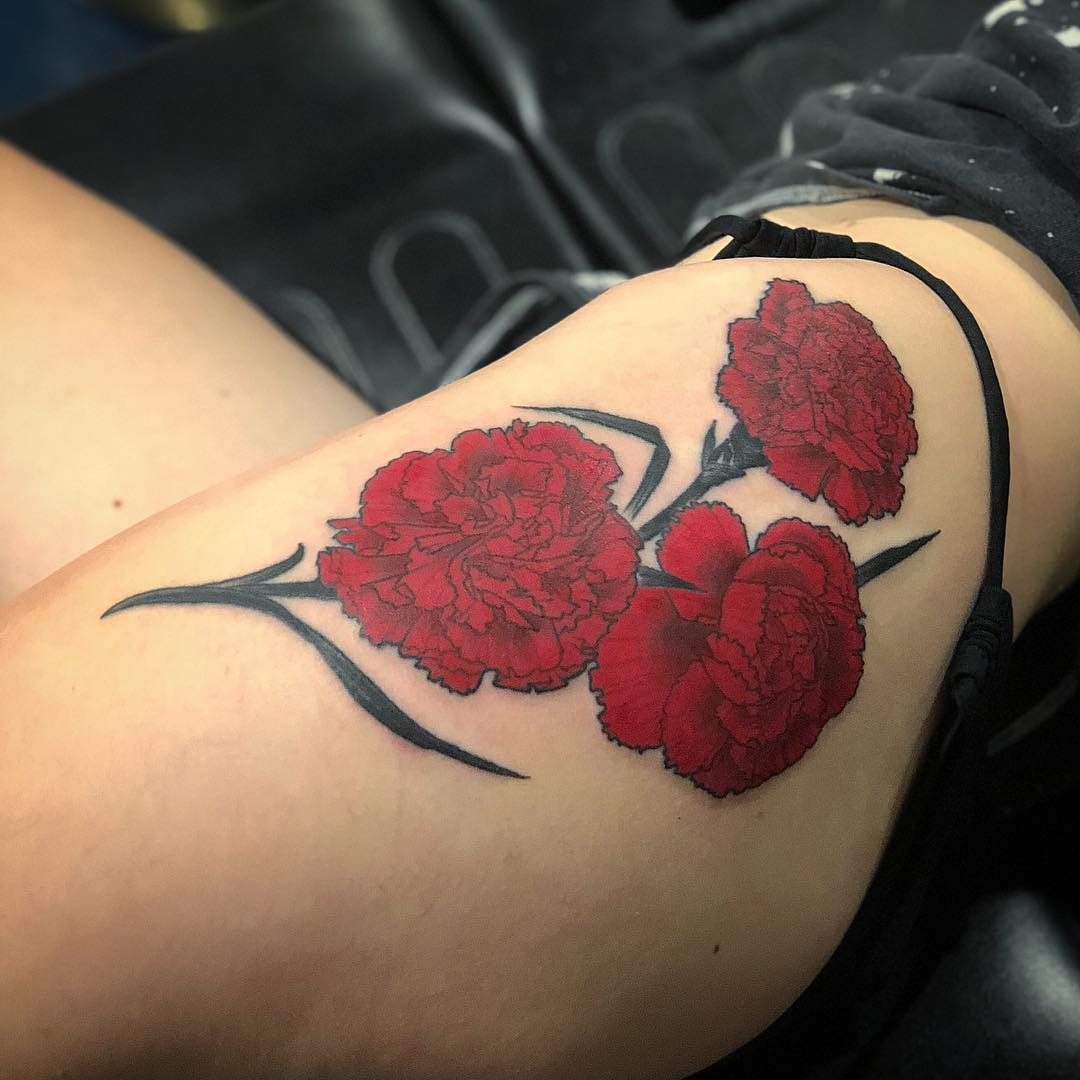 Tatuaje de flor de Clavel en el muslo.