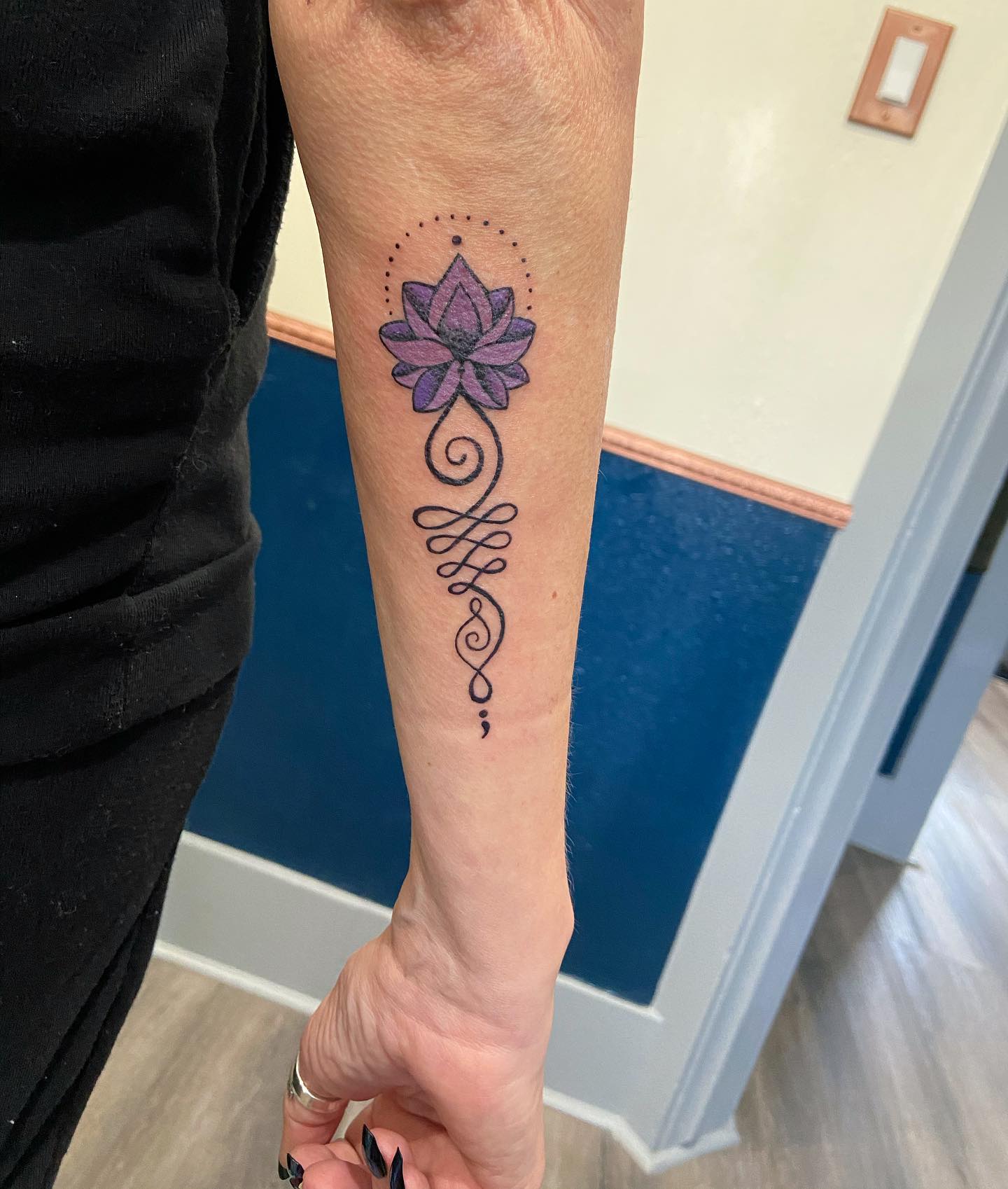 Tatuaje Unalome con flor de loto morada.