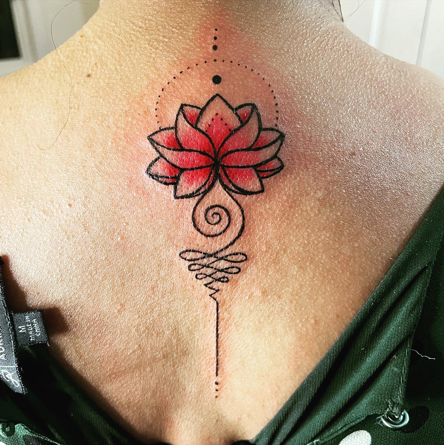 Tatuaje Unalome con una flor de Loto roja.