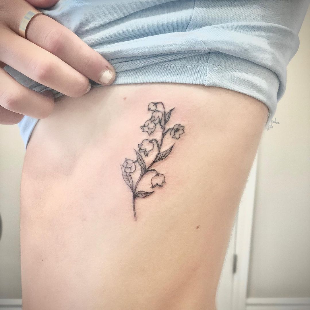 Tatuaje de flor pequeña en las costillas del lado negro.