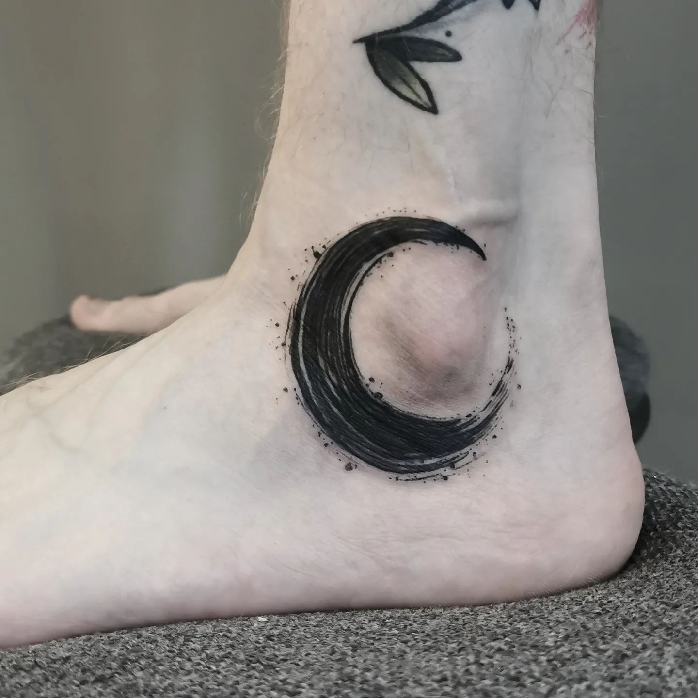 Tatuaje de luna en el tobillo.
