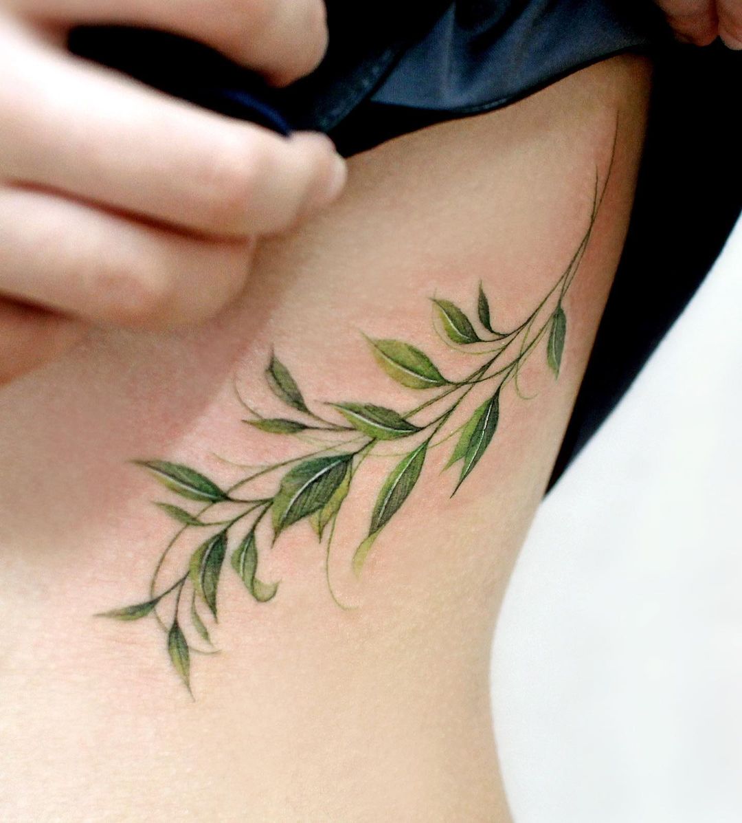 Tatuaje de mariposa verde en las costillas laterales.
