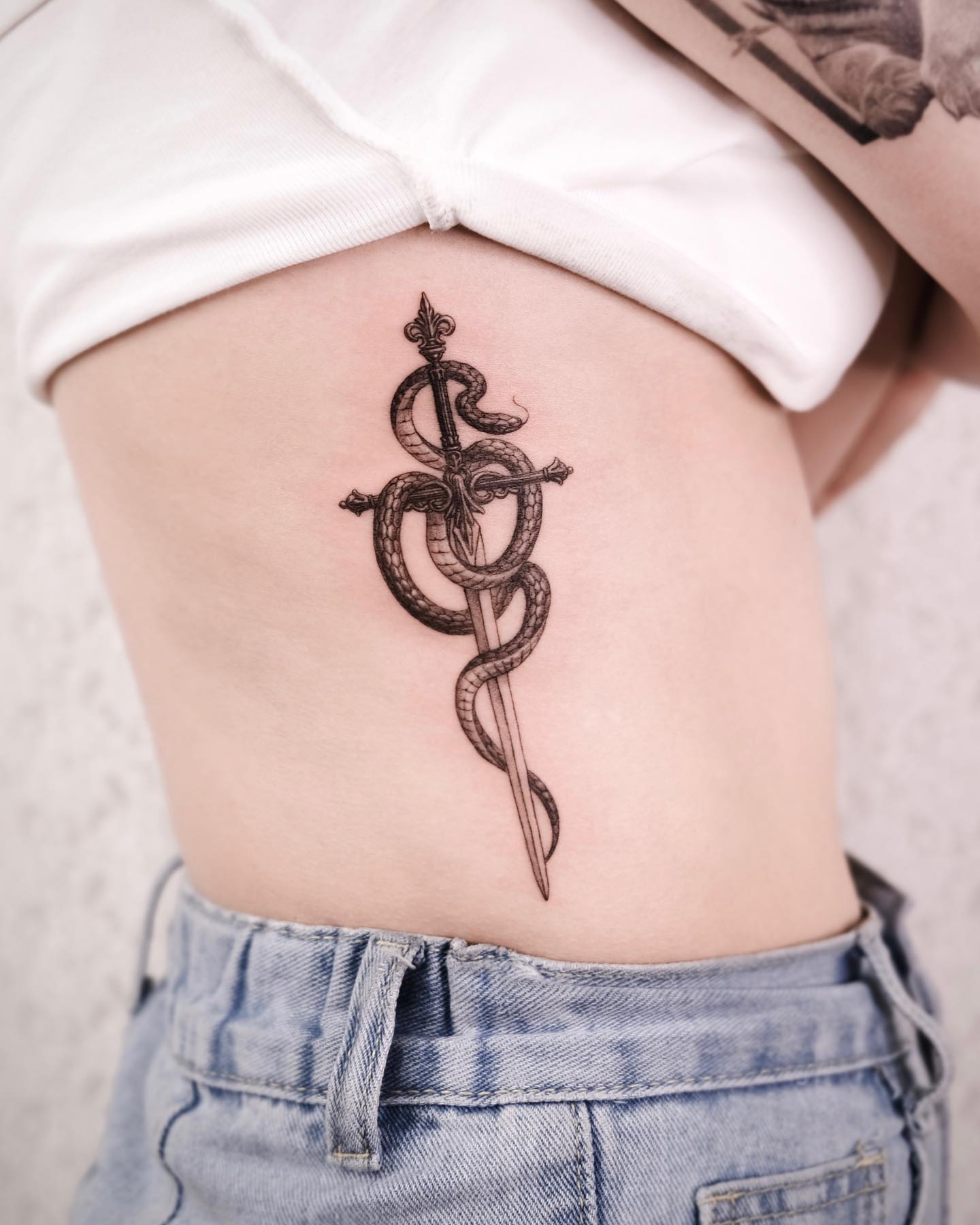Tatuaje de serpiente y espada en las costillas del costado.