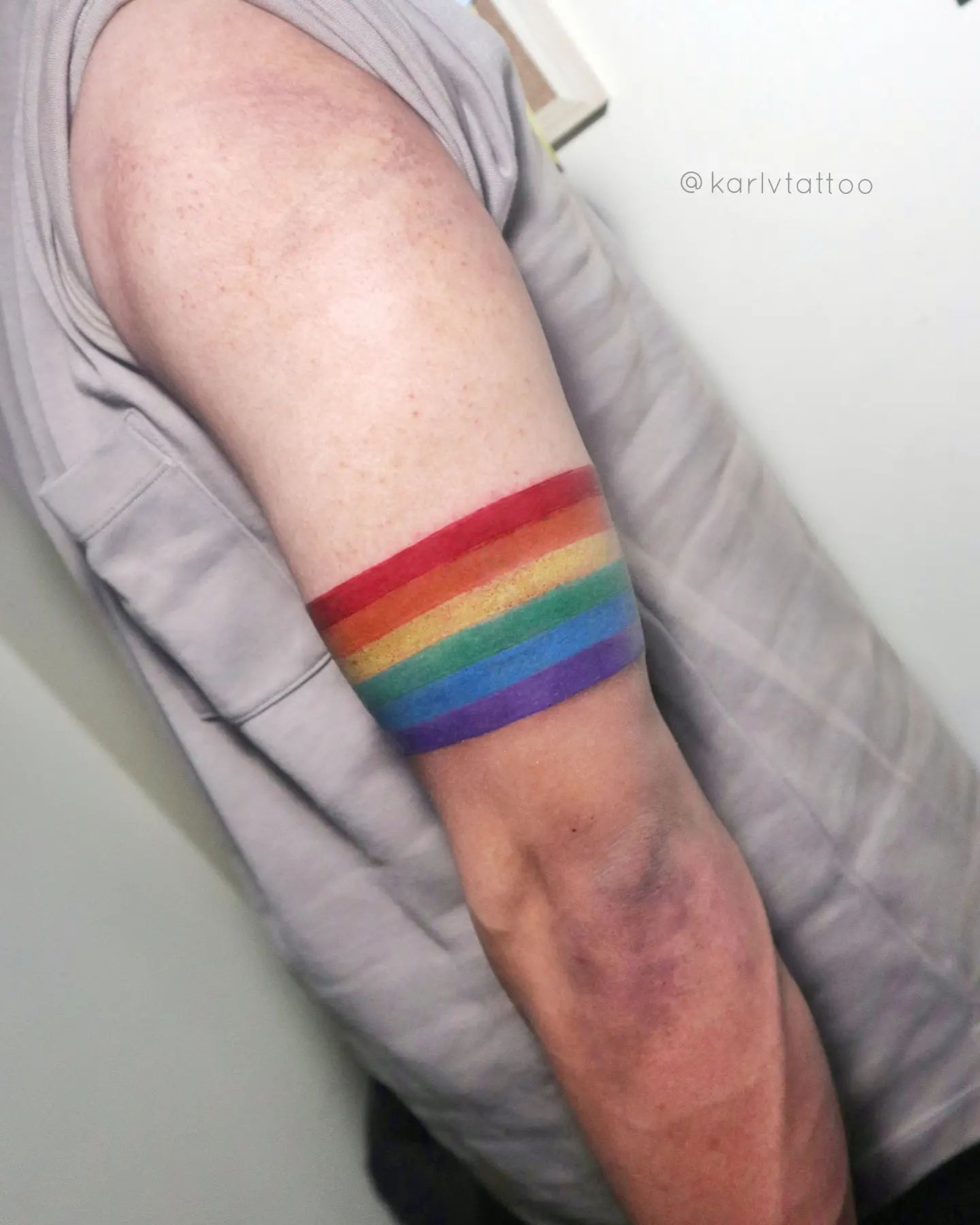 Tatuaje en brazalete con diseño de arcoíris.