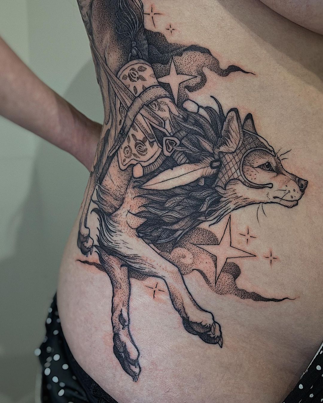 Tatuaje negro de un lobo en el costado de las costillas.