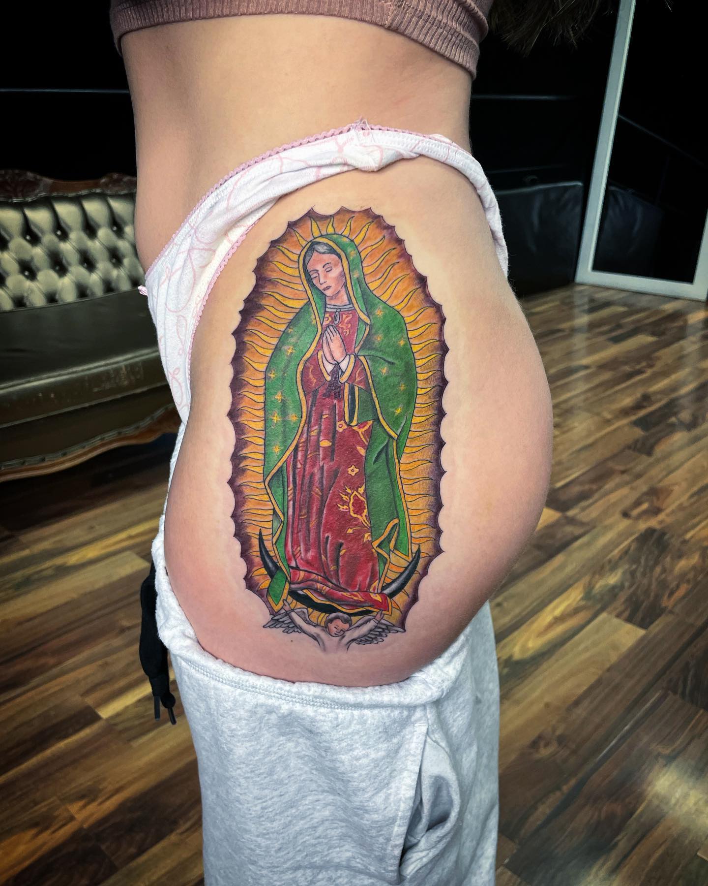 Tatuaje de la Virgen de Guadalupe en el muslo.