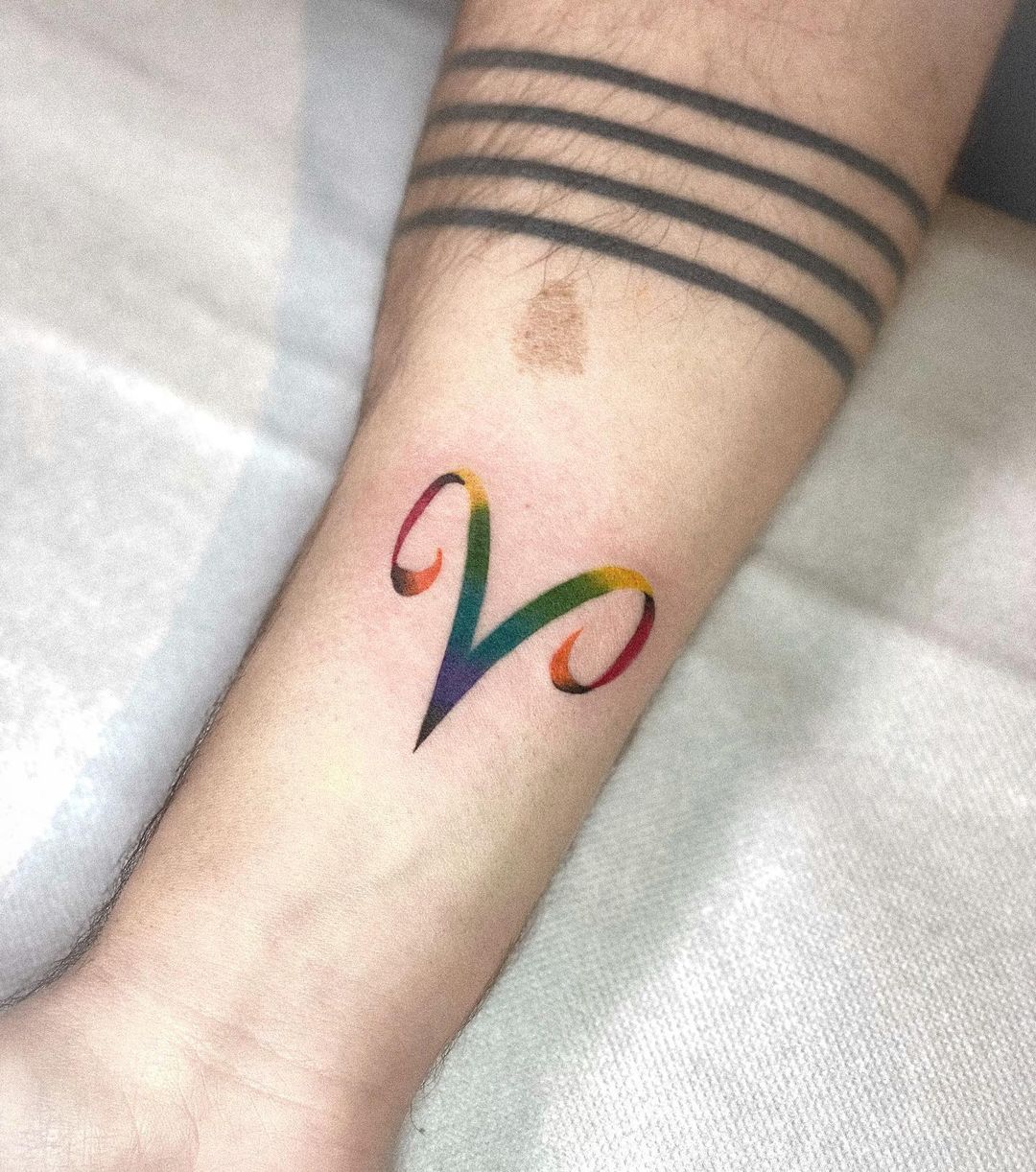 Tatuaje colorido de Aries en el brazo.