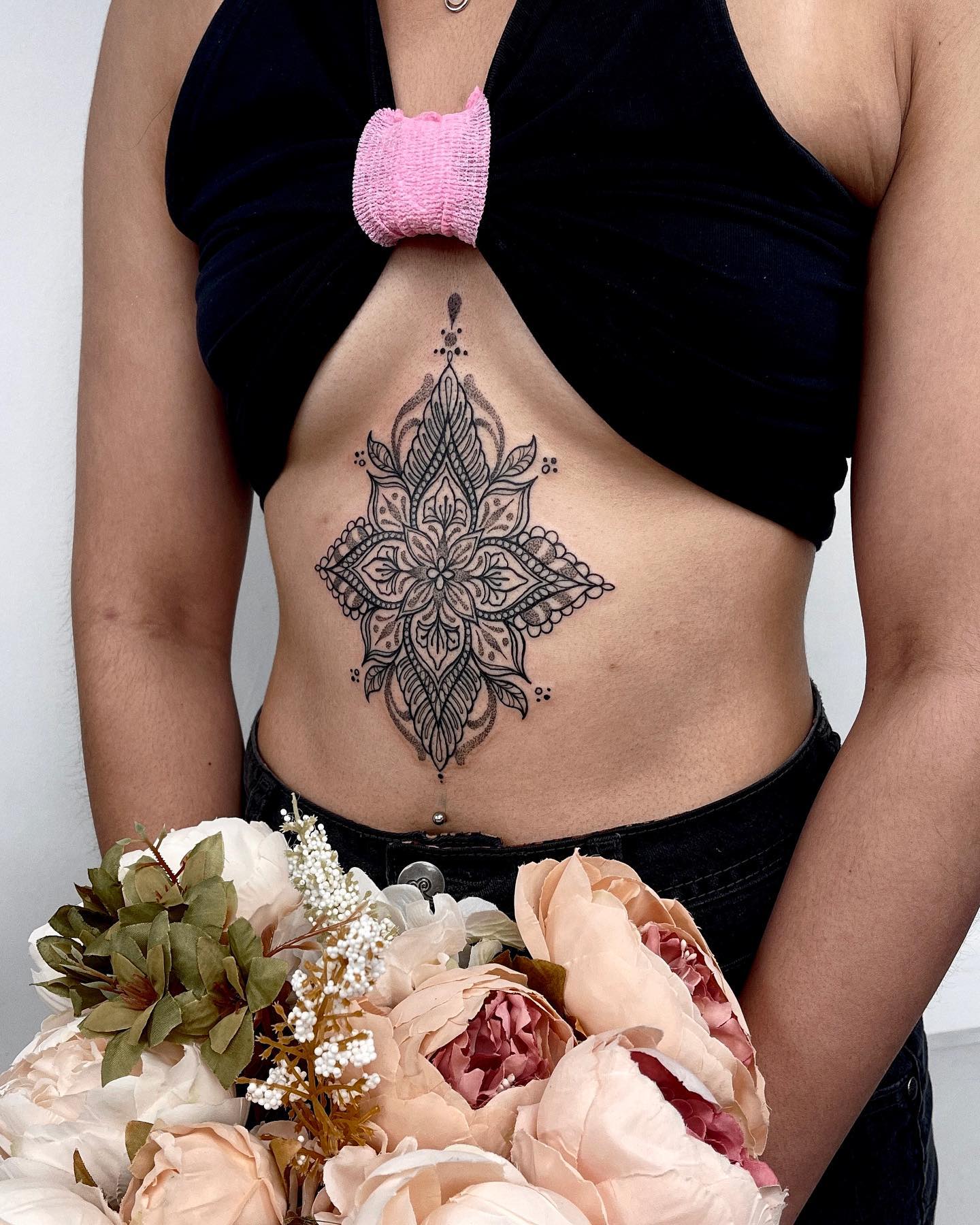 Tatuaje de gran mandala entre los senos.