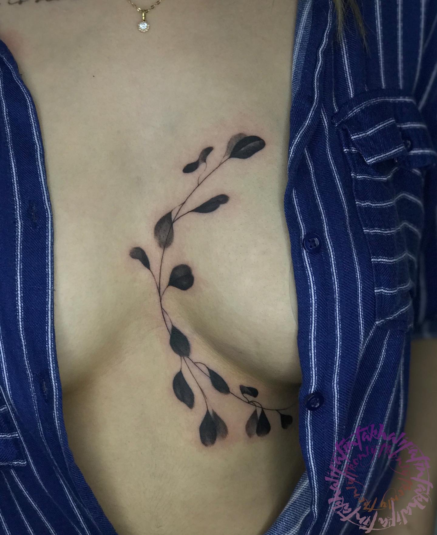 Tatuaje de hoja negra entre los senos