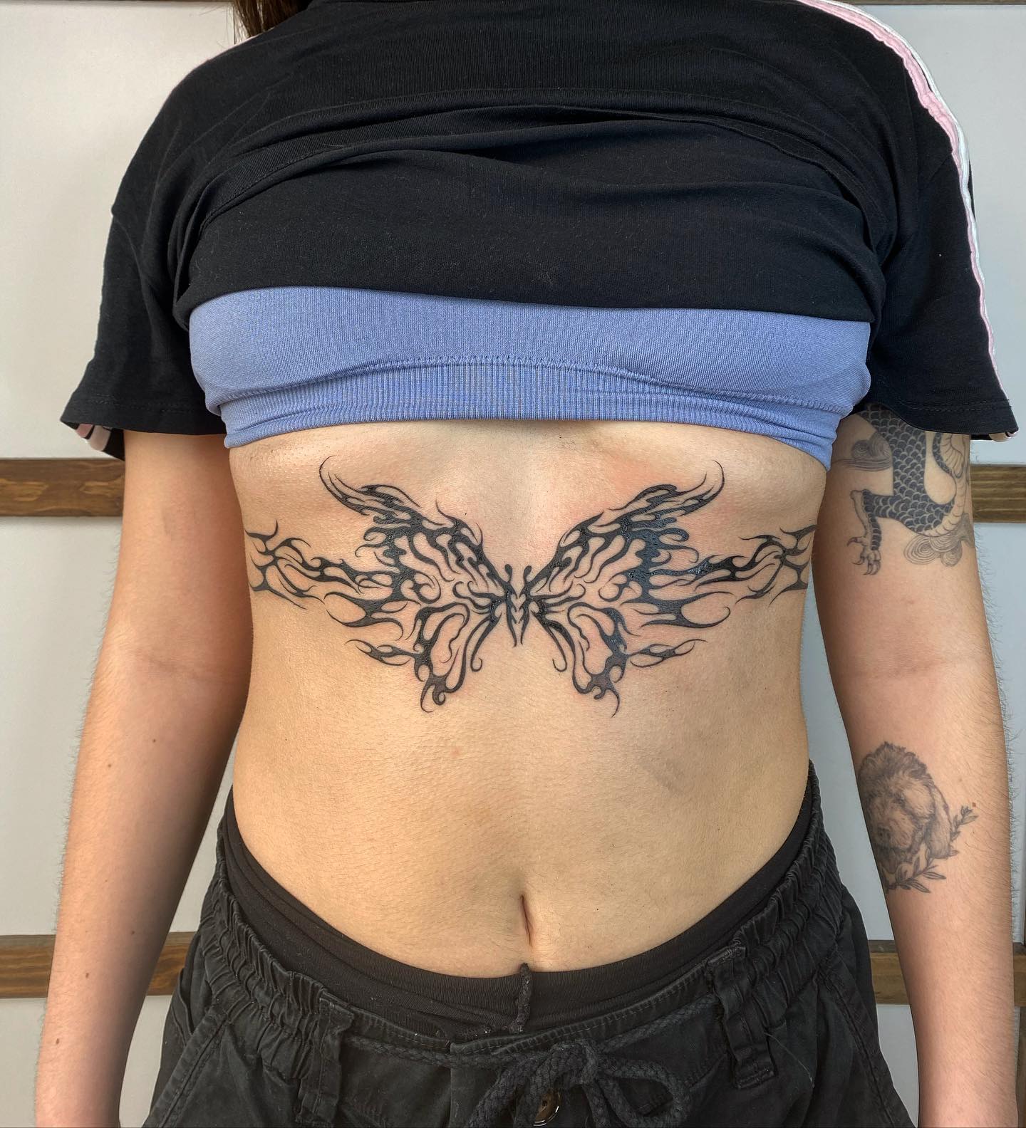 Tatuaje de mariposa diseñado entre los pechos.