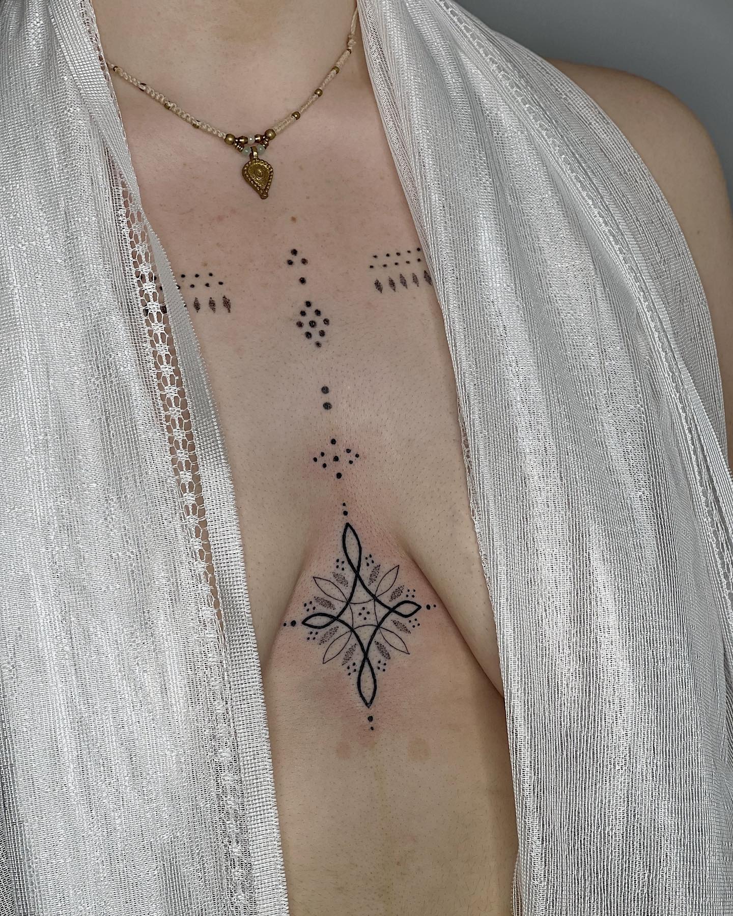 Tatuaje de puntos pequeños entre los senos