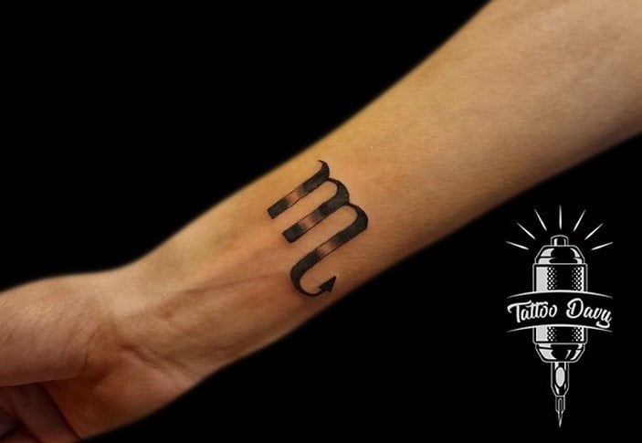 Tatuaje de símbolo de Escorpio en el brazo.