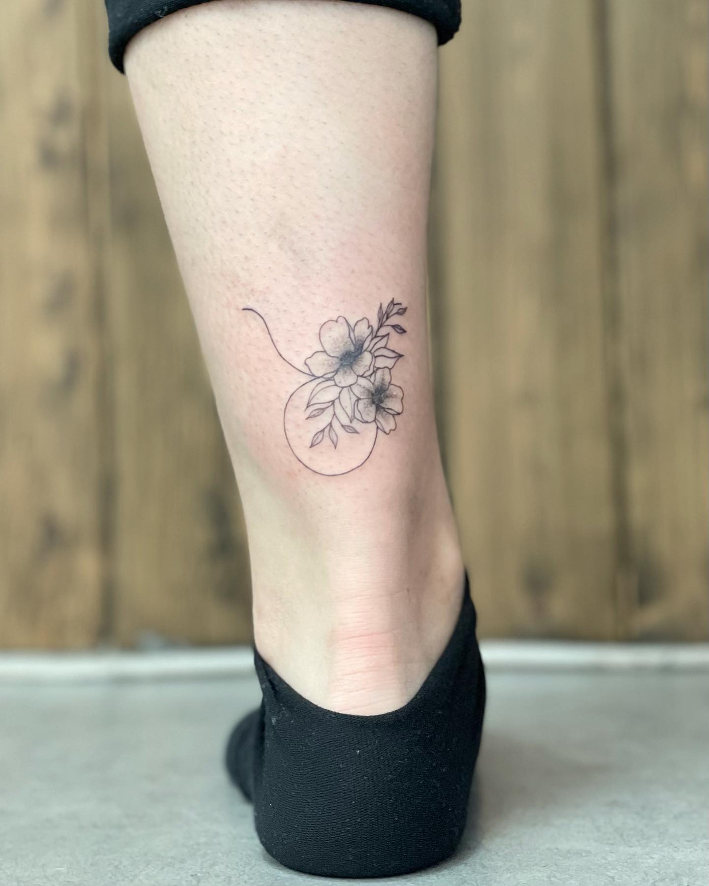 Pequeña flor tatuada con línea fina.
