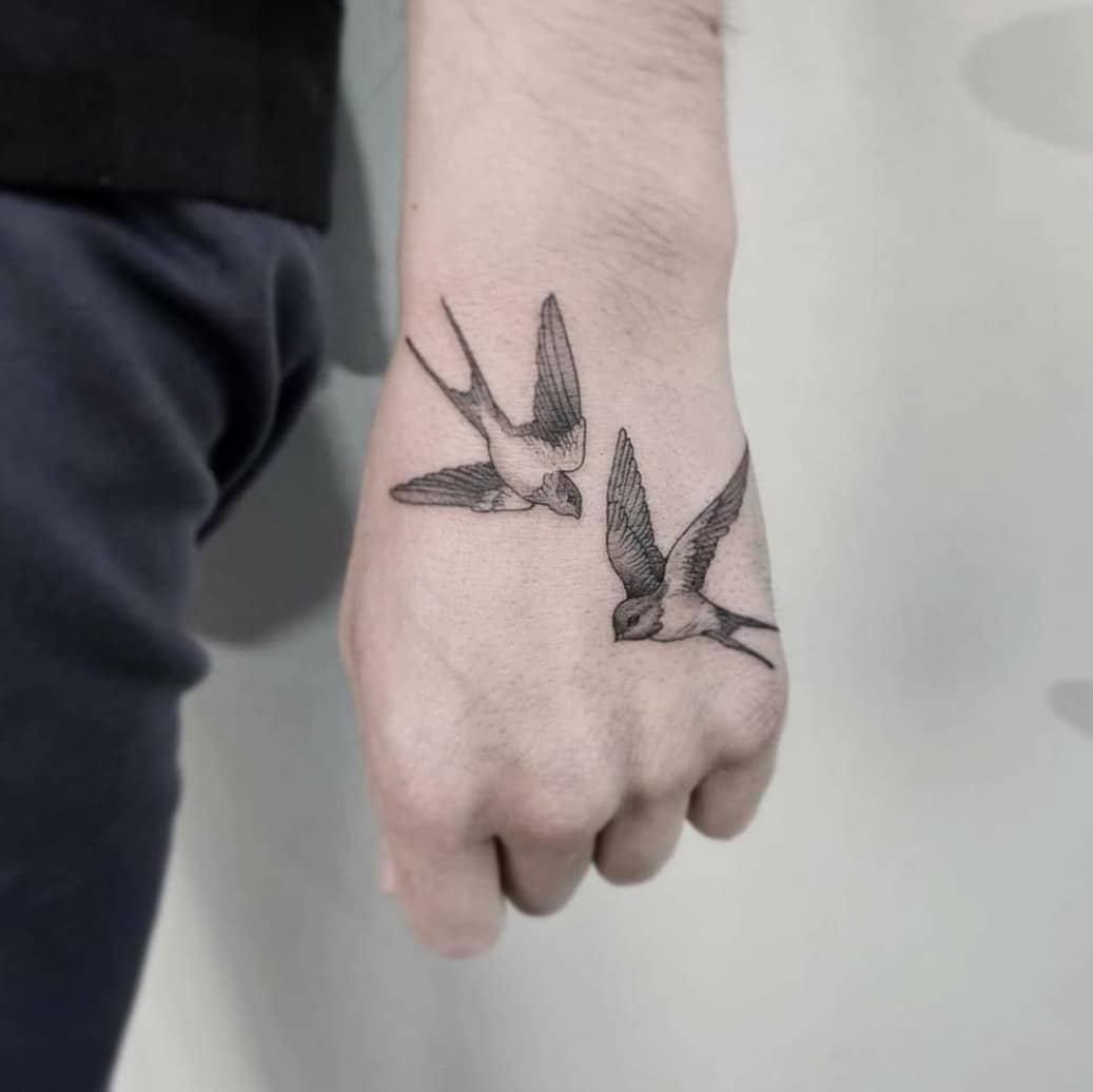 Tatuaje de dos pájaros con tinta negra.