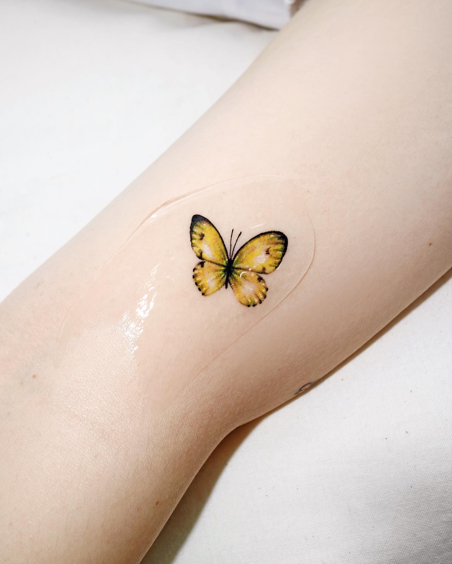 Pequeña mariposa amarilla tatuada.