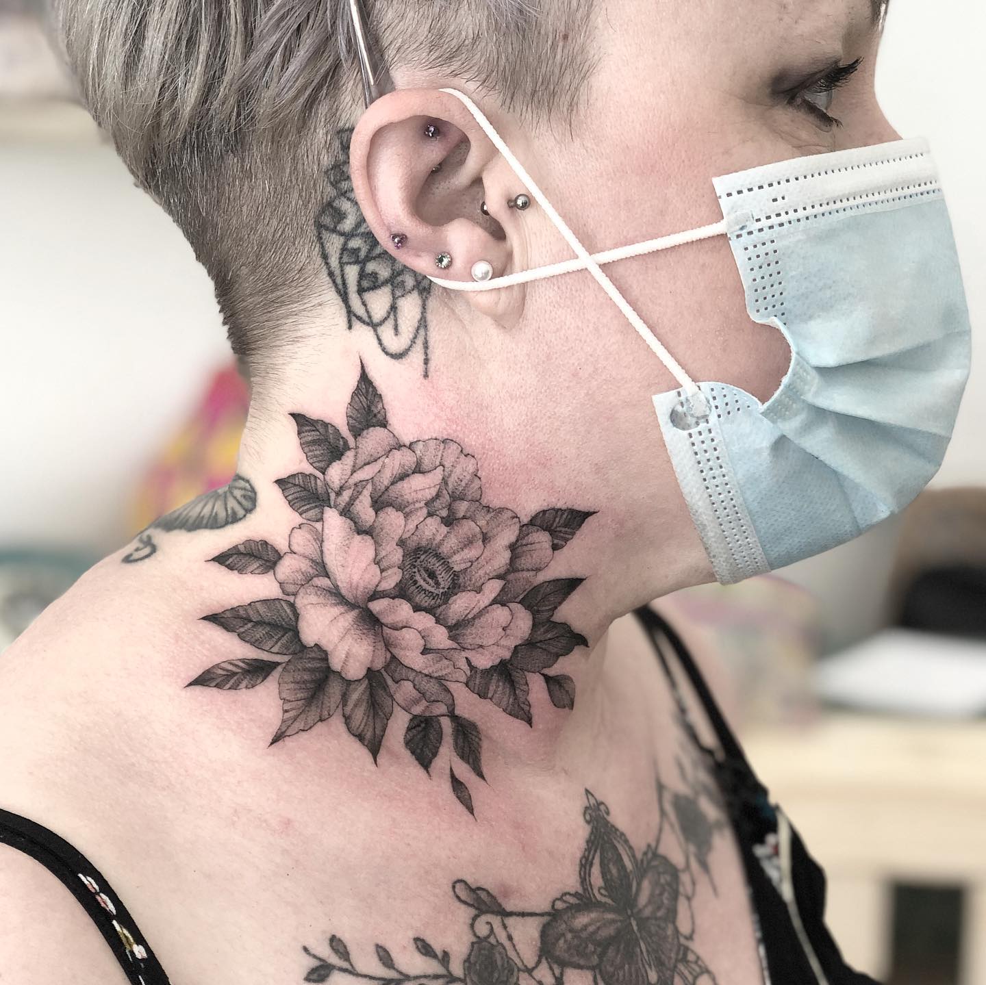 Tatuaje de flor de peonía en el cuello.