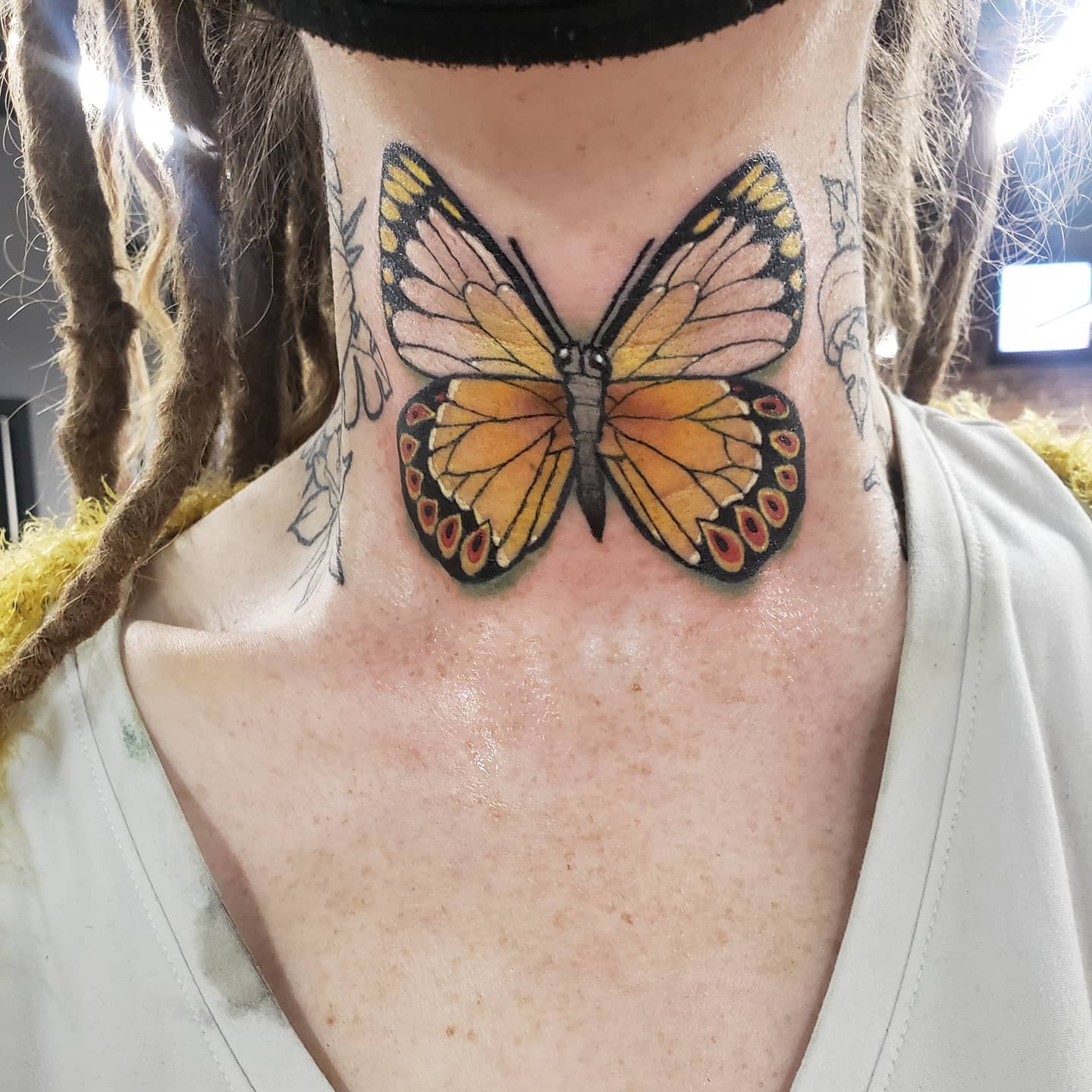 Tatuaje de mariposa en el cuello.