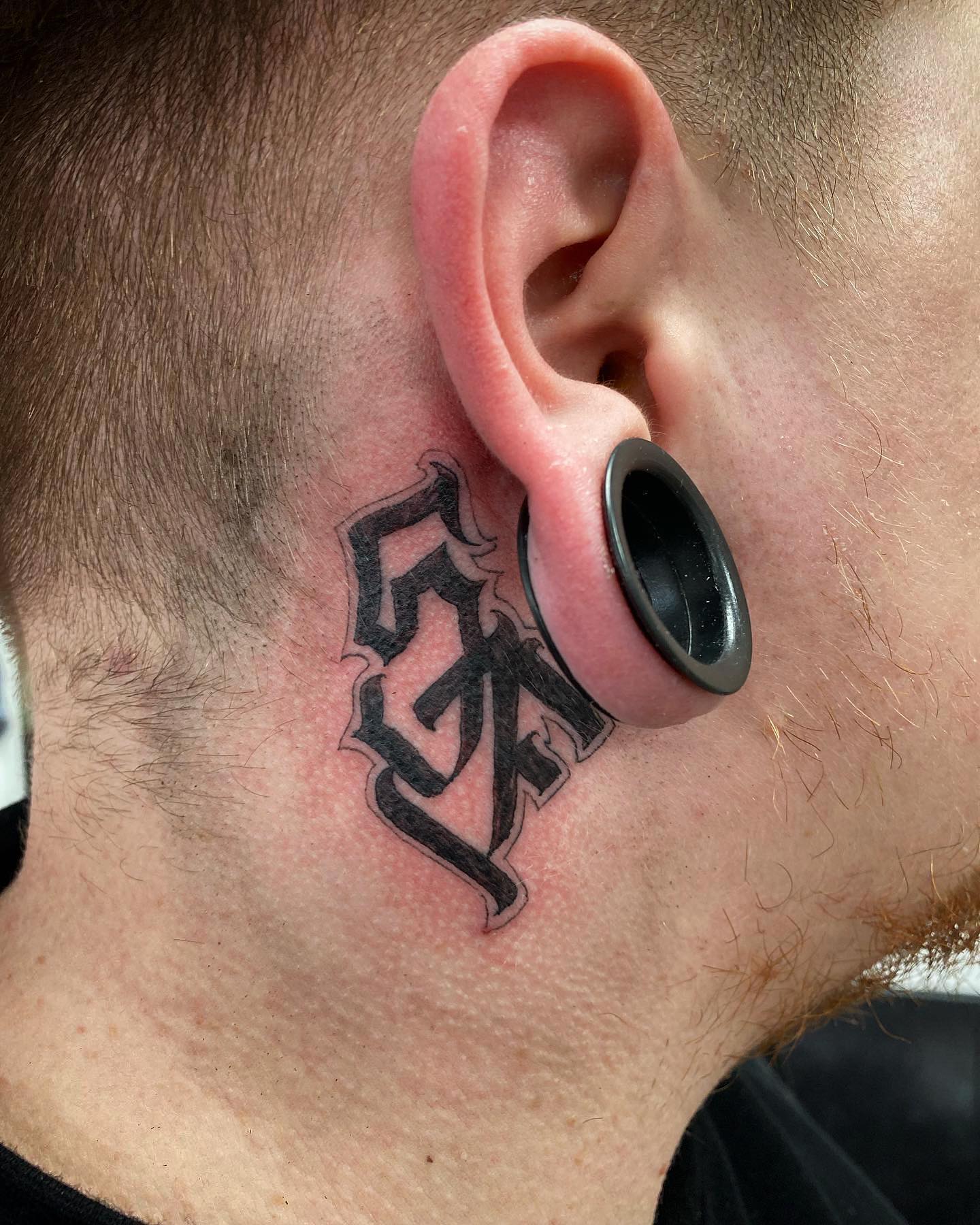 Tatuaje detrás de la oreja para hombres.