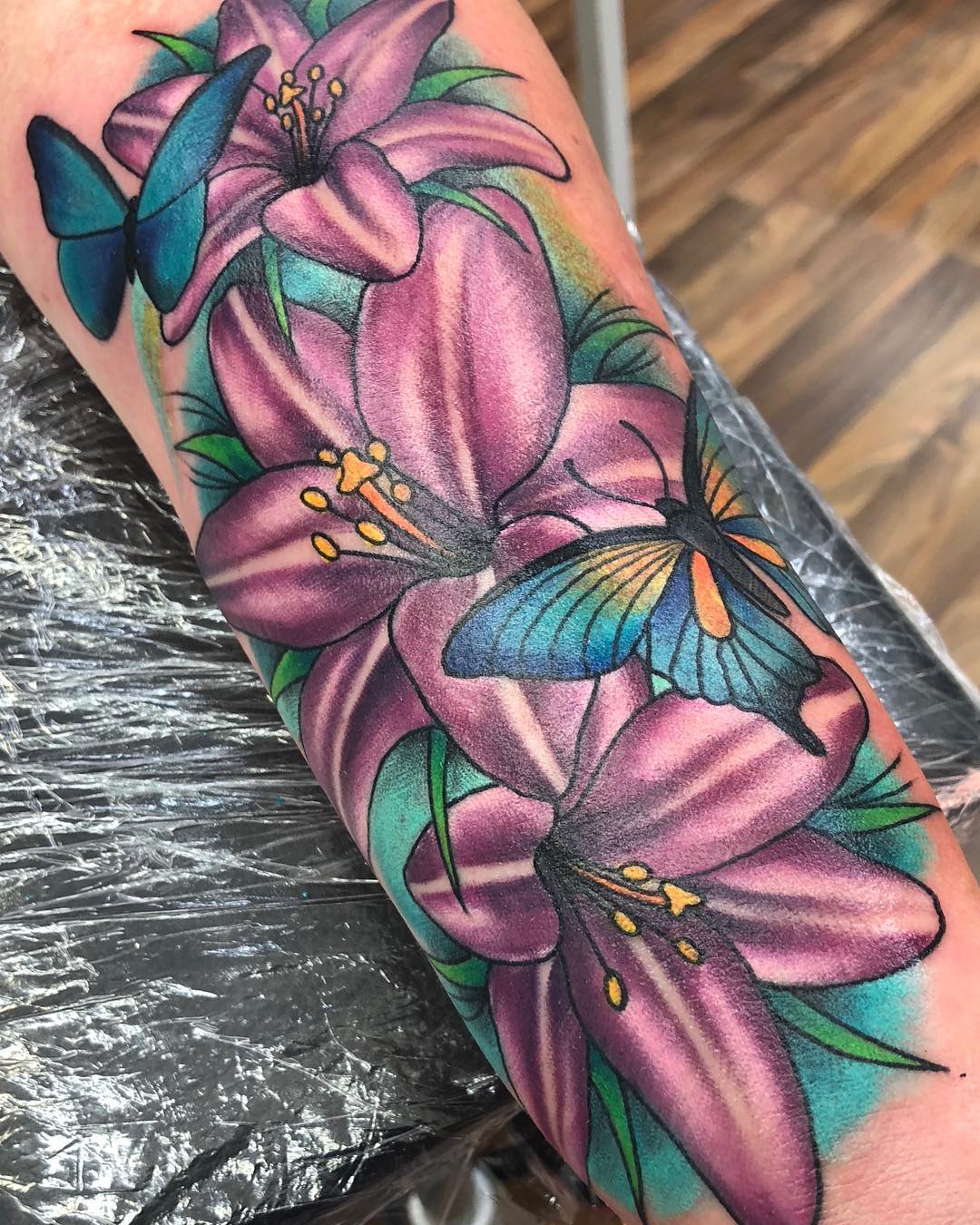 Flores moradas y tatuaje de mariposa en el antebrazo