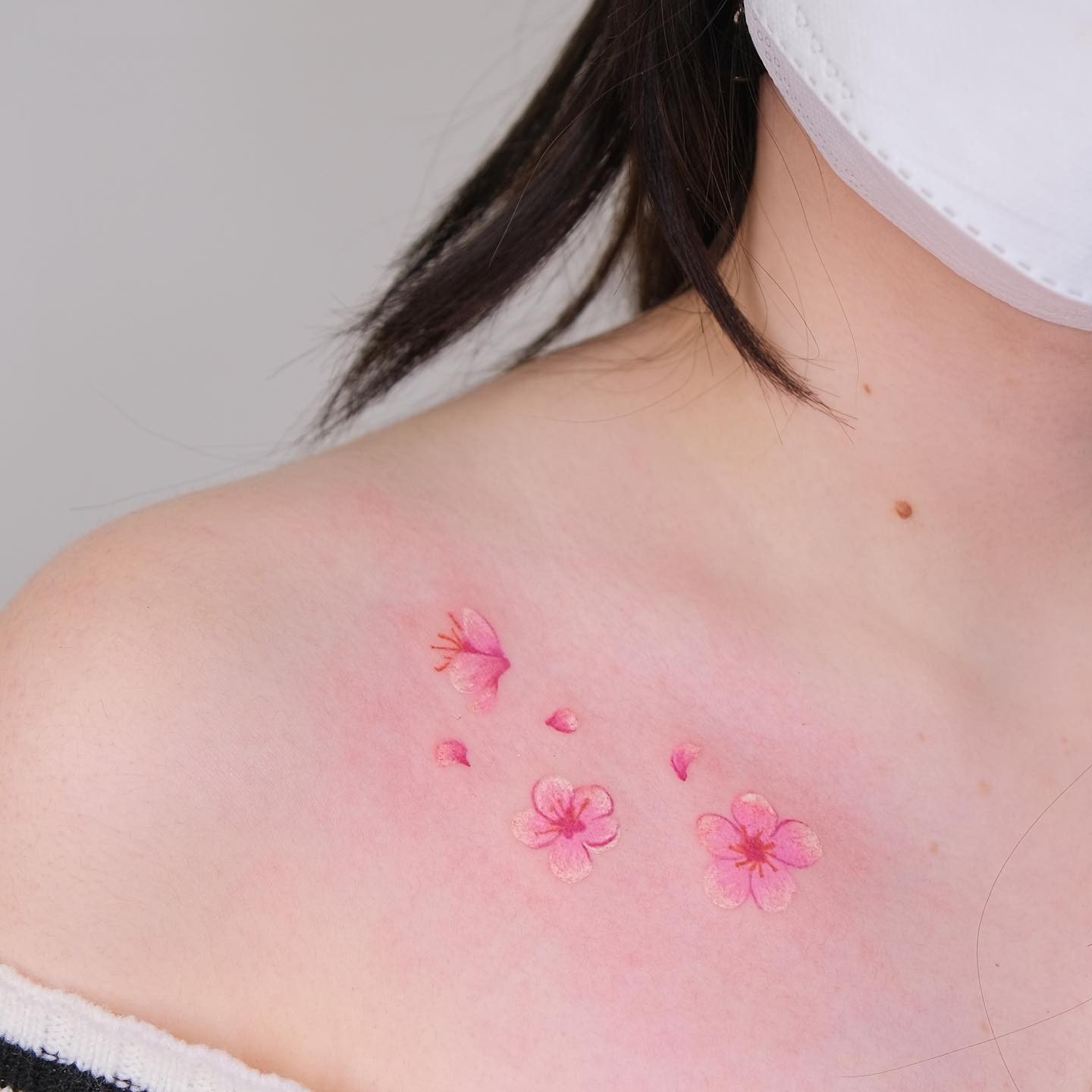 Pequeñas flores rosas tatuadas en la clavícula.