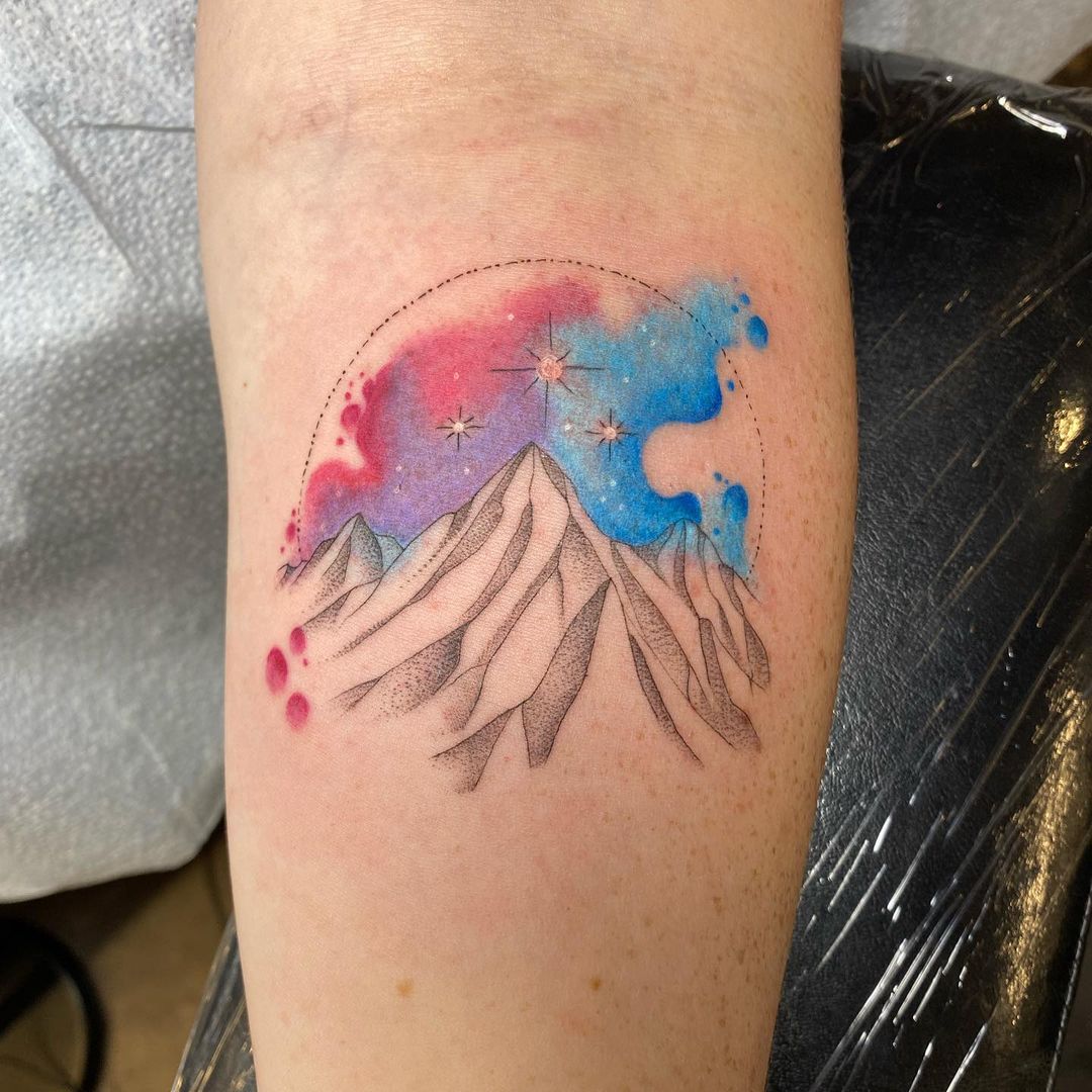 Tatuaje colorido de montaña en el antebrazo