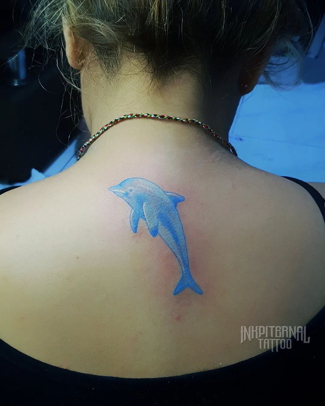 Tatuaje de delfín en el cuello de atrás