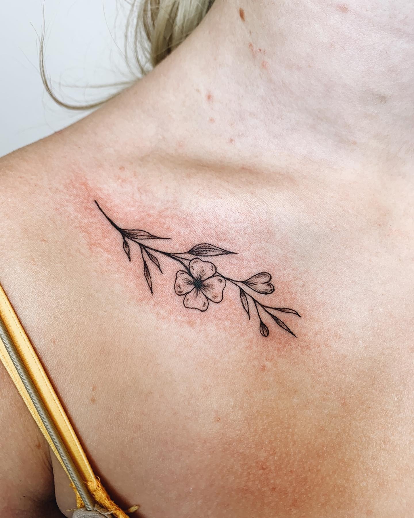 Tatuaje de flores negras en la clavícula