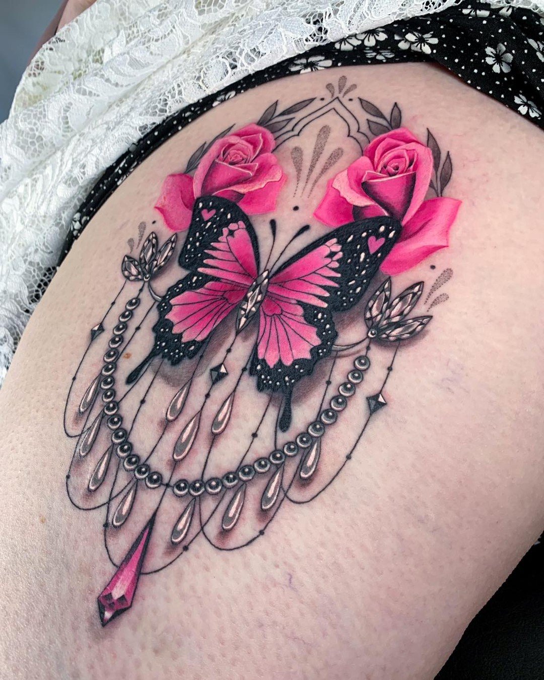 Tatuaje de flores rosas y mariposas en el muslo