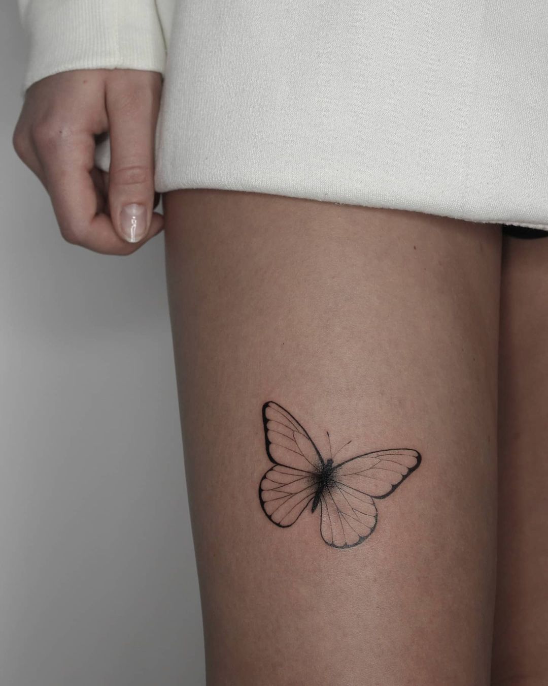 Tatuaje de mariposa lindo en el muslo para mujeres.