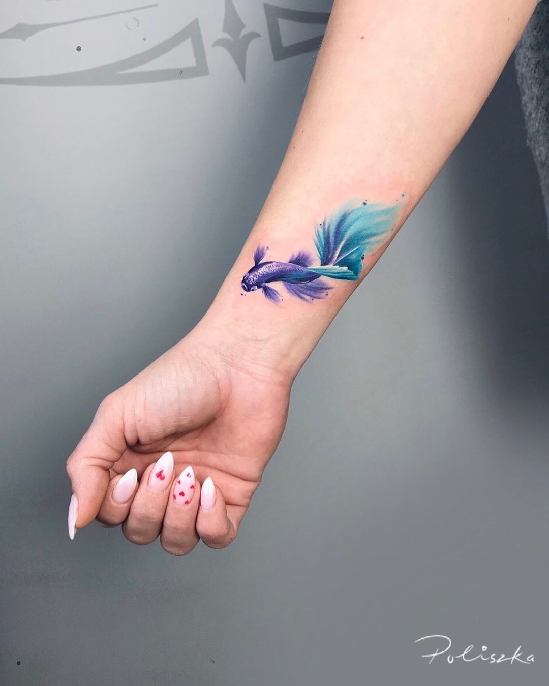 Tatuaje de pez Koi azul en el antebrazo