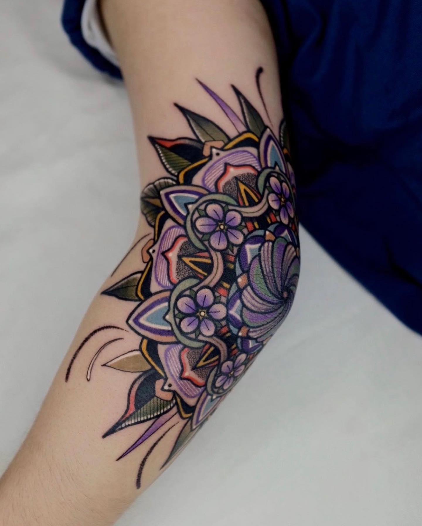 Tatuaje divertido y floral en el codo