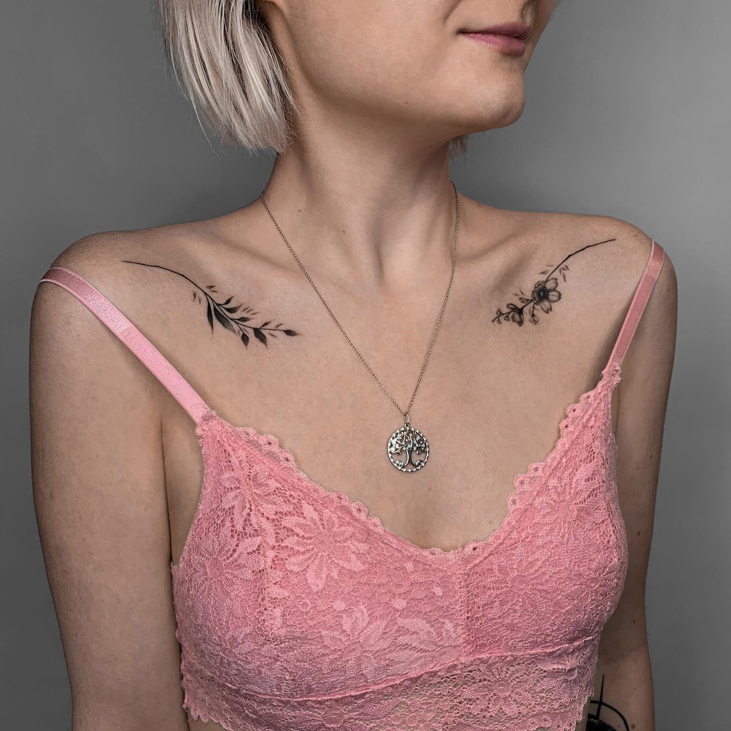 Tatuaje femenino de tinta negra en la clavícula.