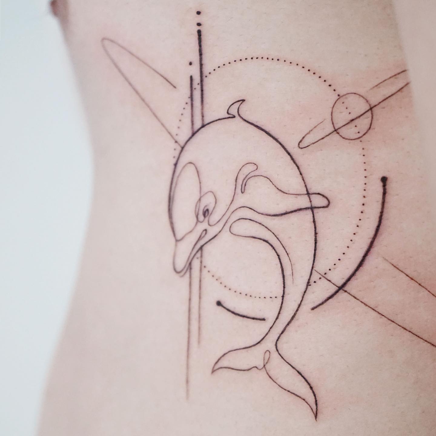 Tatuaje geométrico de delfín artístico.